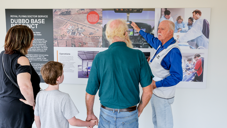 Flying Doctors volunteer guiding a family of three on a tour